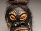 un gros plan d'un masque aux cheveux longs posé sur une surface blanche