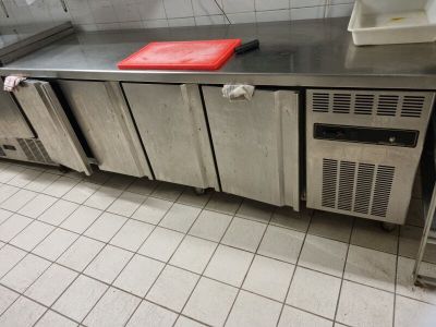 stainless steel counter top in a commercial kitchen with refrigerators and freezers