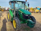 a green tractor that is parked in the dirt