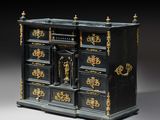 une commode ancienne noire et dorée, surmontée d'une horloge