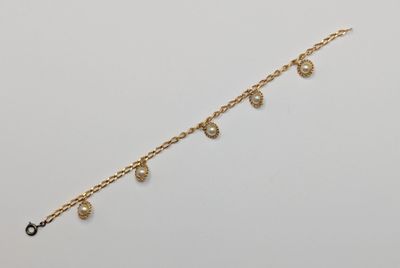 a close up of a gold chain bracelet with pearls on it