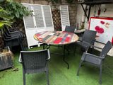 une table et des chaises dans le jardin, avec un tableau accroché au mur