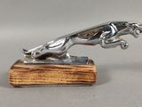 une statue en argent représentant un chien, posée sur un socle en bois