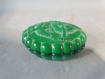 un petit objet vert posé sur une table avec un fond blanc