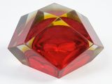 a red and yellow glass object on a white surface