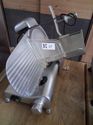 a large meat slicer sitting on a wooden table