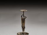 an image of a bronze candle holder with a woman holding a flower