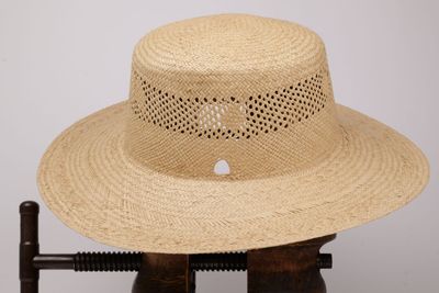 une photo d'un chapeau de paille posé sur un support en bois