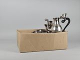 a box with a silver tea pot and two cups in it