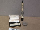 a silver pen and a silver pen sitting on a table next to a silver coin