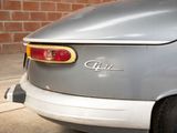 a silver car parked in front of a brick wall