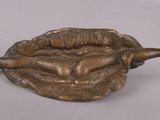 bronze statue of a woman laying on her stomach in a bowl