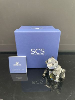 une petite figurine posée sur une table, à côté d'une boîte bleue