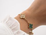 the woman is wearing a gold bracelet with green and white stones