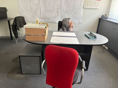 un bureau avec une chaise rouge et un tableau blanc accroché au mur