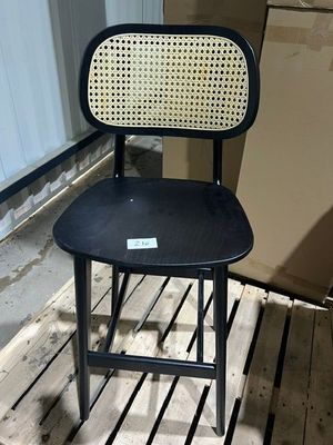 a black chair with a wicker back and seat on a wooden floor