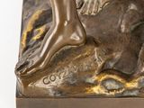 bronze statue of a person standing on a rock with their feet on the ground