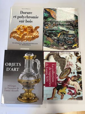 trois livres posés sur une table, avec un vase doré et d'autres objets