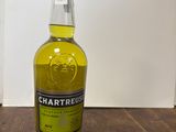 La bouteille de Chartreuse est posée sur une table en bois.