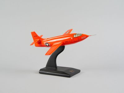 une maquette d'avion orange posée sur un socle noir