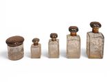 four glass bottles with wooden lids and lids on a white surface