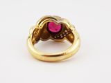 a close up of a gold ring with a pink stone in the center