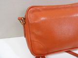 an orange leather purse sitting on top of a white table