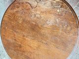 a round wooden table with a wooden top on a tile floor