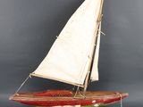 un petit voilier en bois muni d'une voile blanche