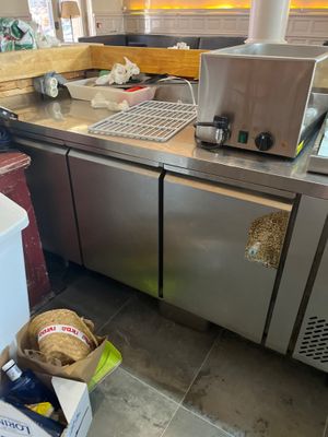stainless steel counter top in a commercial kitchen with a bag of bread on the floor