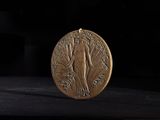 a gold medal on a black surface with a black background