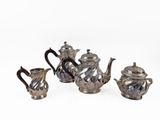four pieces of silver tea and coffee set on a white surface