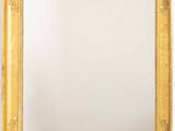 un miroir encadré d'or sur un mur blanc avec un fond blanc