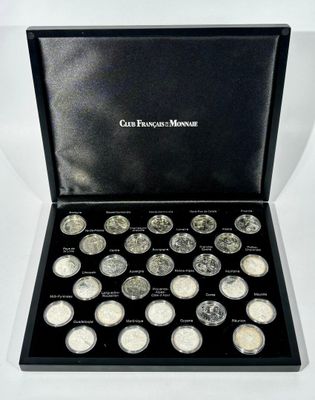 a black box filled with silver coins sitting on top of a white surface