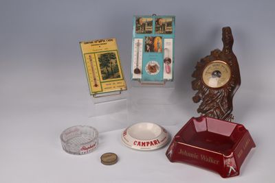 une petite horloge posée sur une table, à côté d'un paquet de cigarettes