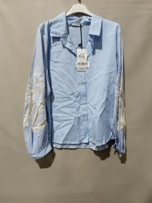 chemise à rayures bleues et blanches avec des manches en dentelle, suspendue à un cintre