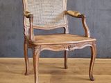 an old wooden chair with wicker seat and armrests on a wooden floor