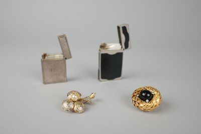 deux paires de boucles d'oreilles et un briquet posés sur une surface blanche
