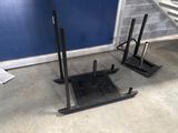 two black stands on the floor next to a blue wall
