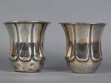 two silver vases sitting next to each other on a table