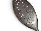 a silver spoon with a design on it on a white surface