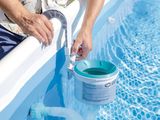 someone using a hose to clean a pool with a bucket of water