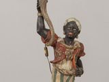 a statue of a man holding a candelier on a table