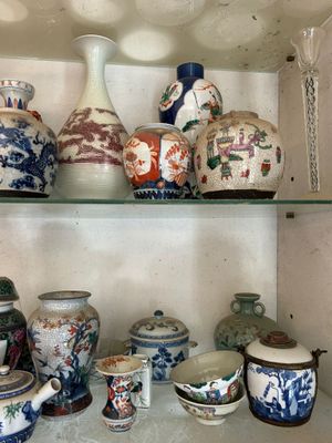 many vases and bowls on a shelf in a cabinet