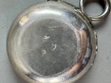 a silver pocket watch with a chain on a table