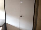 a white cabinet in the corner of a room next to a table