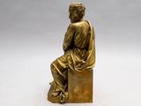 bronze statue of a man sitting on a block with his back to the camera