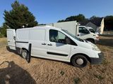 une camionnette blanche garée dans un champ avec d'autres véhicules