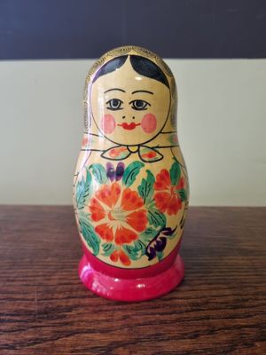 brightly colored matry doll sitting on a wooden table in front of a blackboard