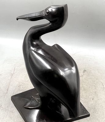 statue of a pelican sitting on a black base with a white background